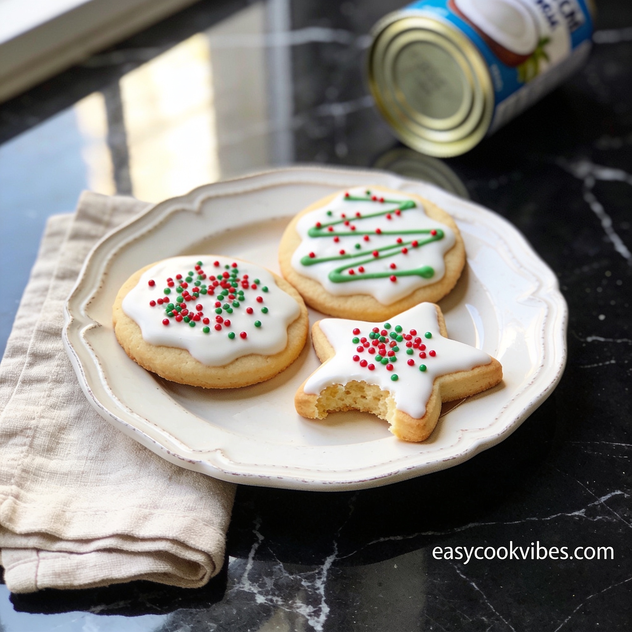 Hero shot of decorated gluten free sugar cookies with coconut milk on black marble with linen napkin